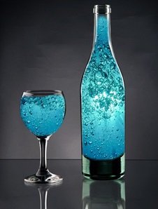 Fles en glas gevuld met blauw gemagnetiseerd water vol bubbels, symbool voor levend water
