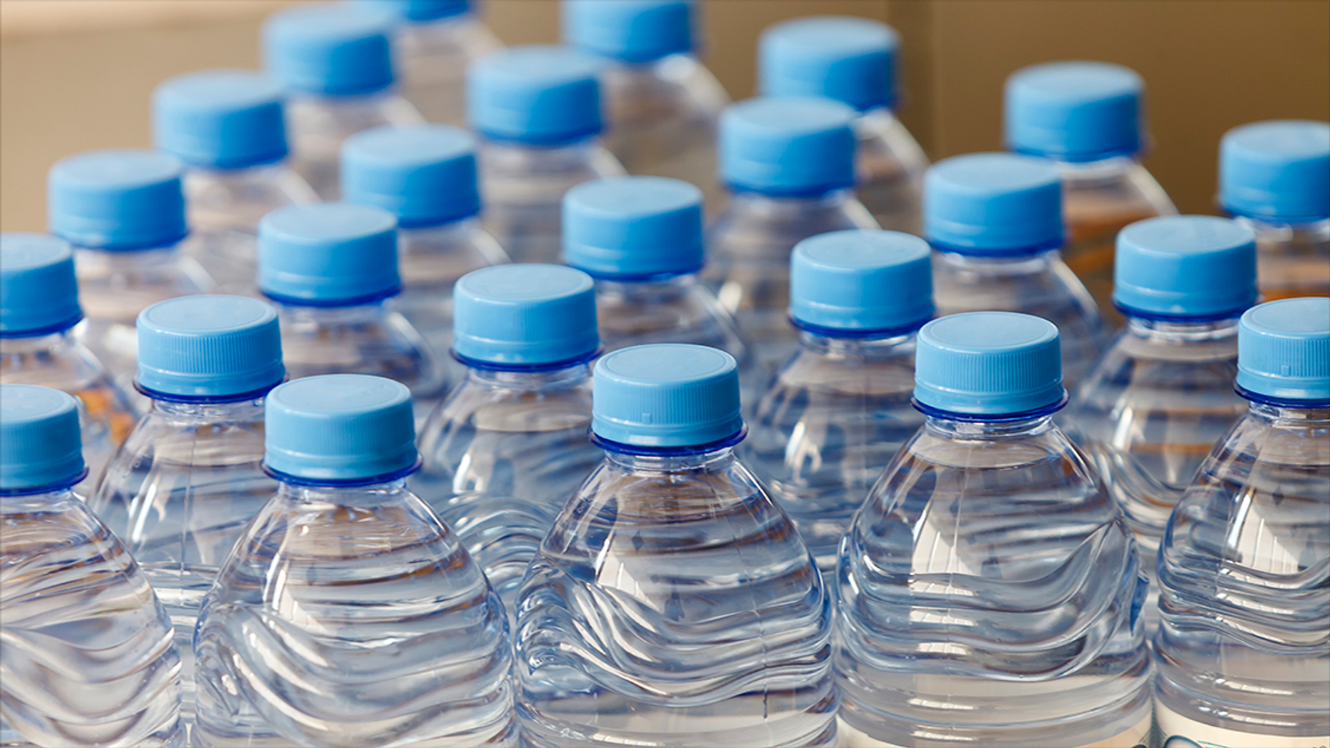 Plastic PET-waterflesjes die mogelijk nanoplastics afgeven aan drinkwater, met risico’s voor gezondheid en celactiviteit.